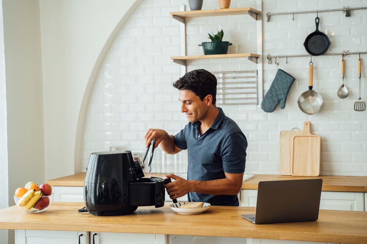 man using air fryer in kitchen