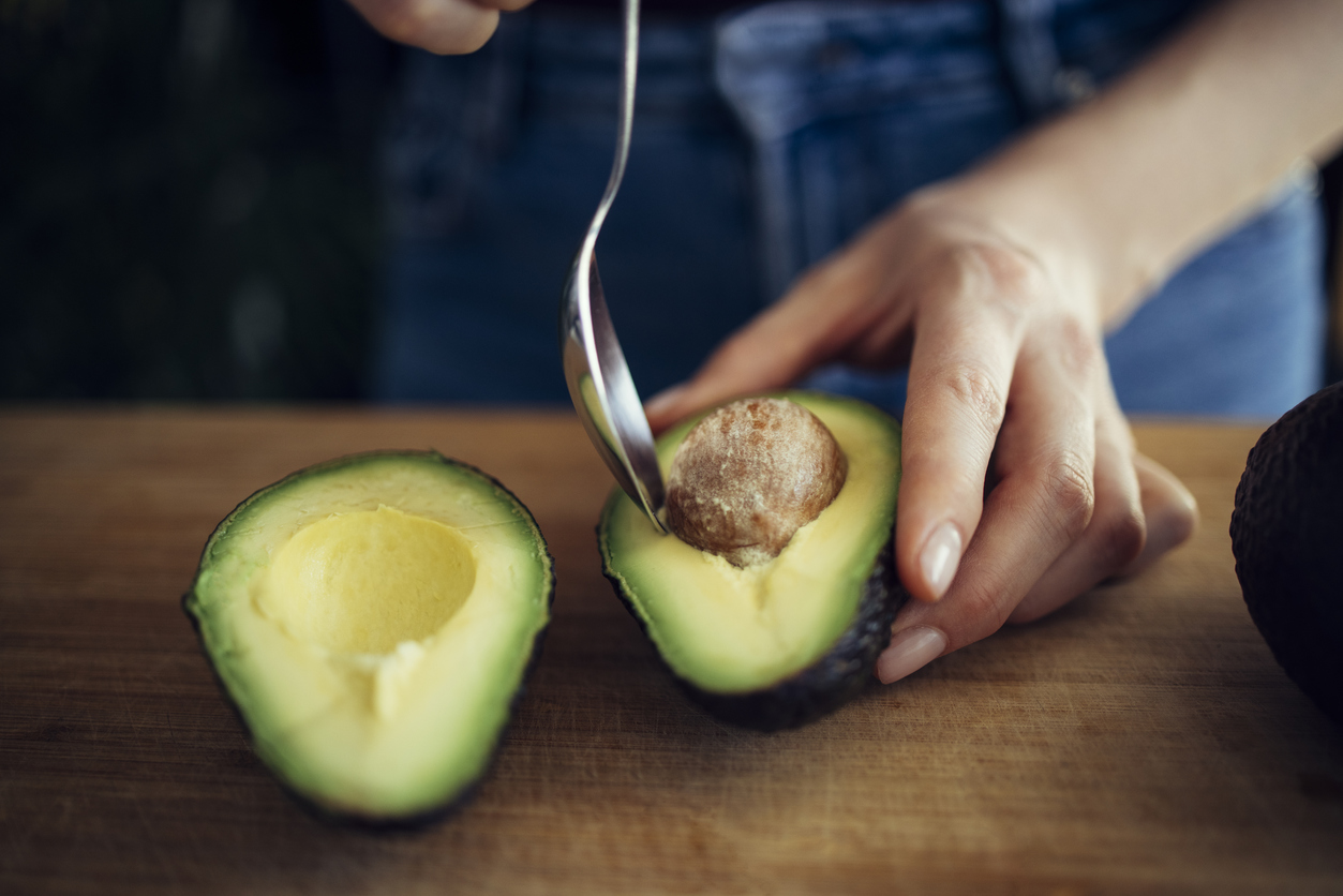 Close Up Photo of Woman Removing Seed from Avocado Half with Spoon