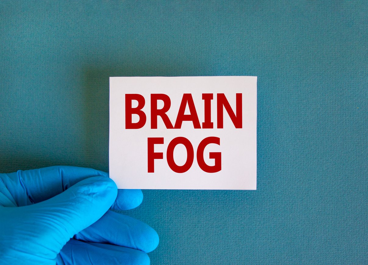 Medical, COVID-19 Pandemic Coronavirus brain fog symbol. Doctor hand holds White card with words 'brain fog'. Metallic pen. Beautiful white background. Copy space. Medical, covid-19 brain fog concept.