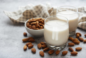 Glasses filled with almond milk and a bowl of almonds on a table