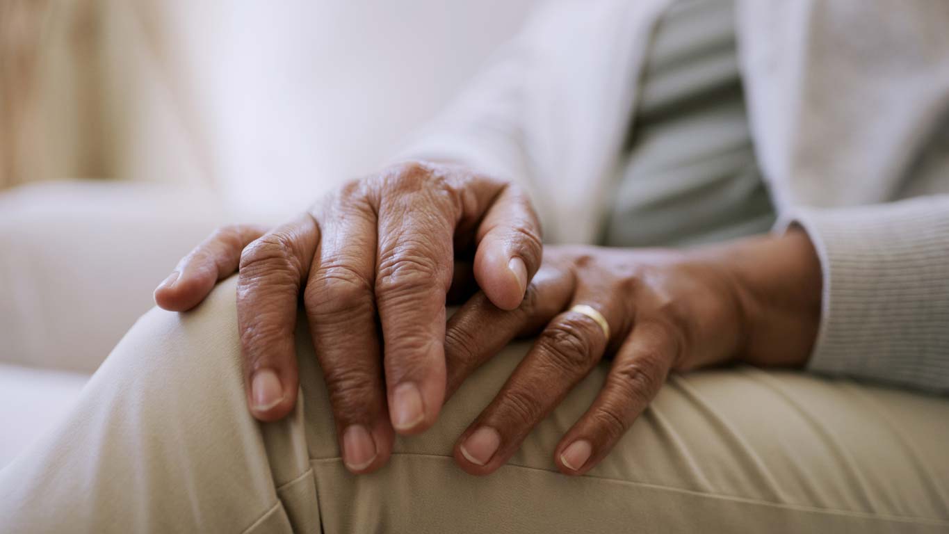 close up of hands sitting on knee showcasing nail health