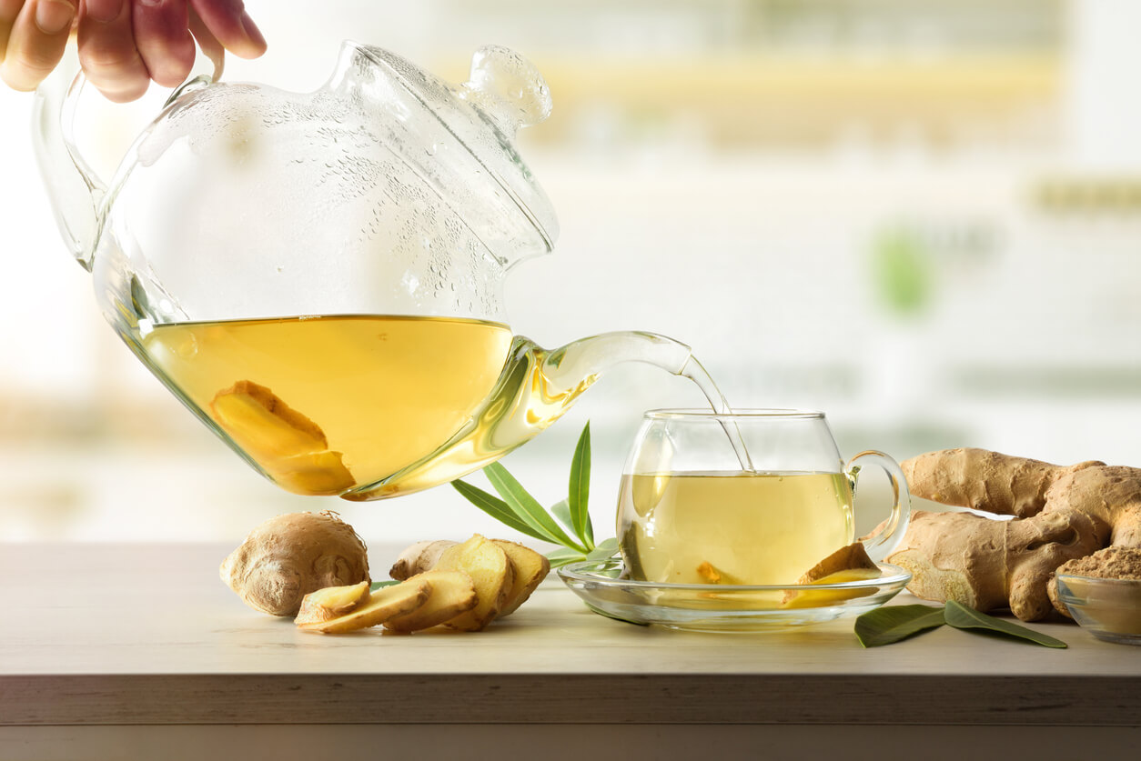 man serving cup with ginger root infusion on kitchen bench