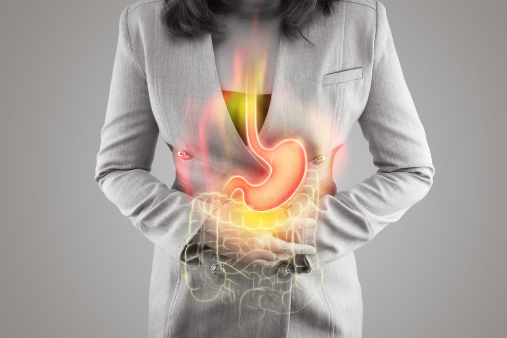 The illustration of stomach and large intestine is on the woman's body against gray background. Acid reflux. Female anatomy