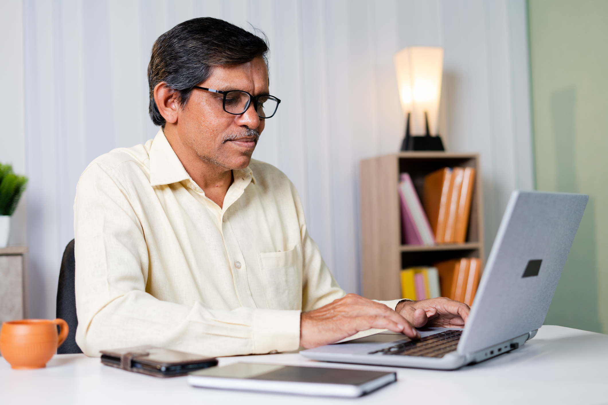 Businessman smiling while working or chatting on laptop at office - concept of using technology, communication and internet.