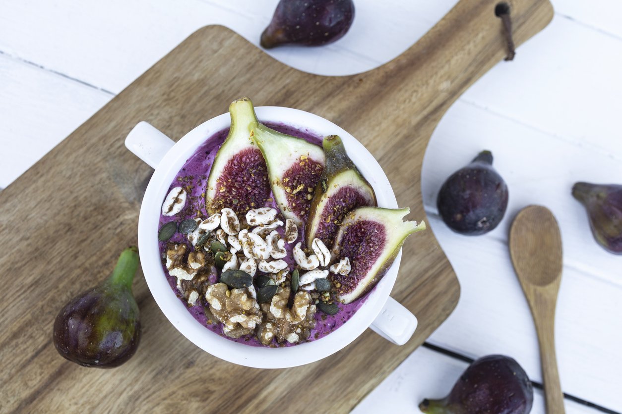 Red fruits smoothie with figs, cereals and nuts. Healthy and vegan bowl for breakfast