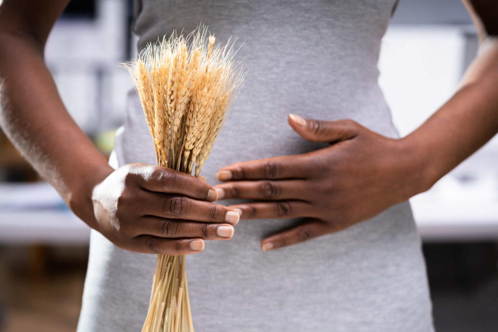 Black woman holding wheat in one hand and holding stomach with her other hand