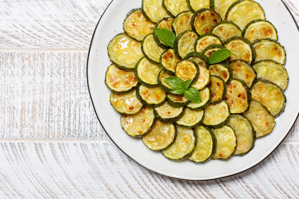 Close-up of roasted young zucchini on white wooden table