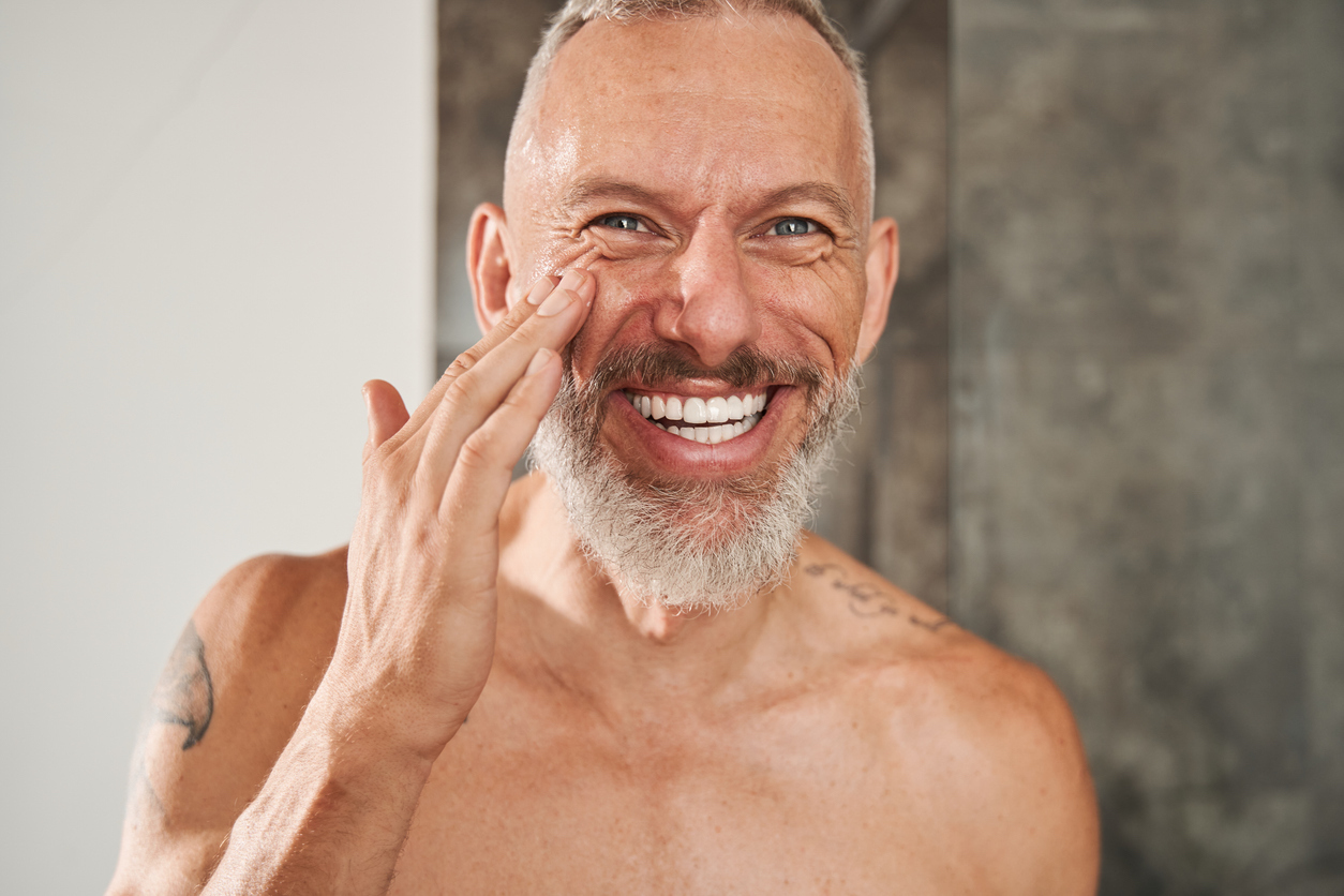 Mature man applying anti-aging cream on his face