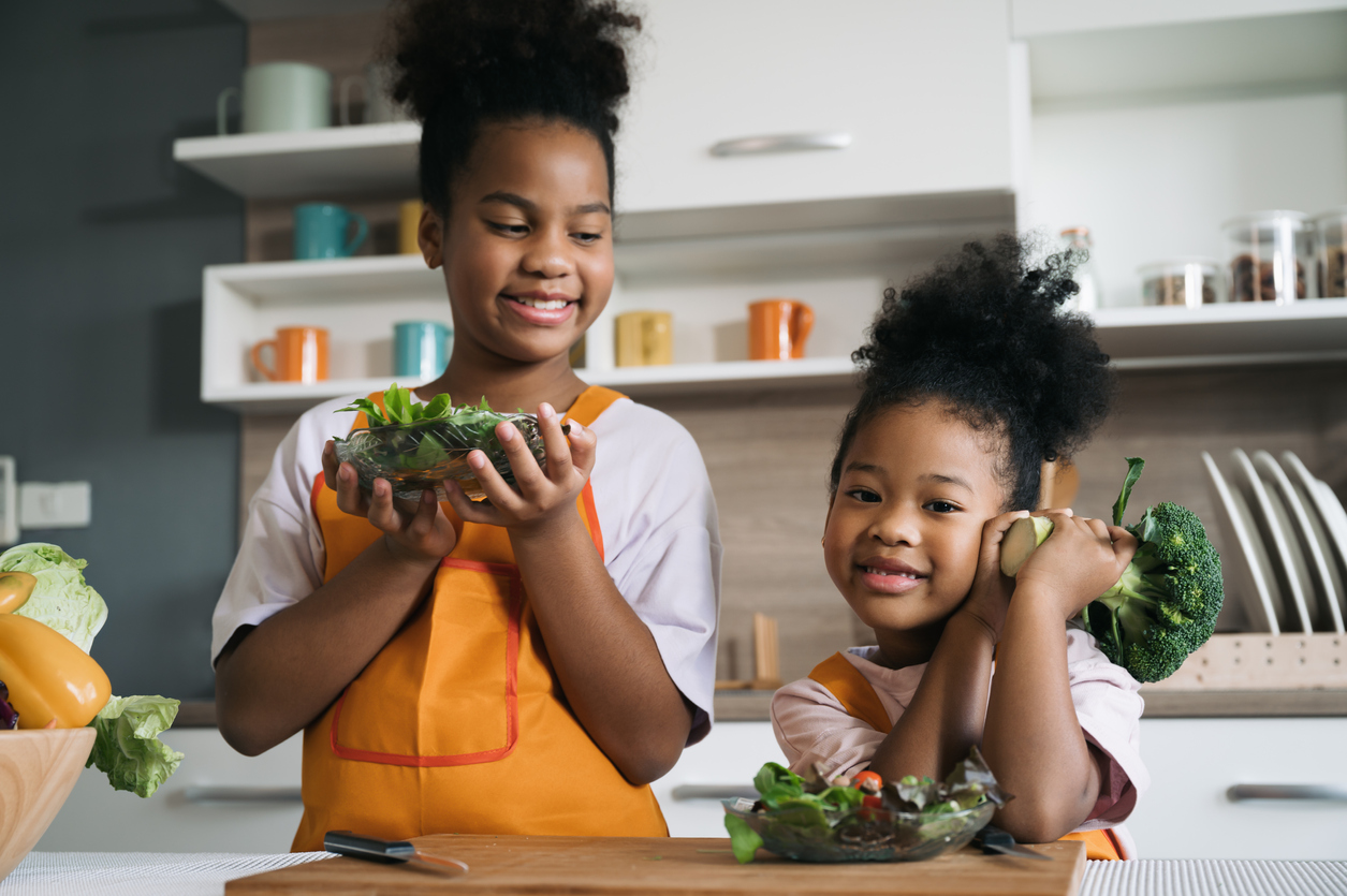 Happy child black skin with vegetable salad in kitchen
