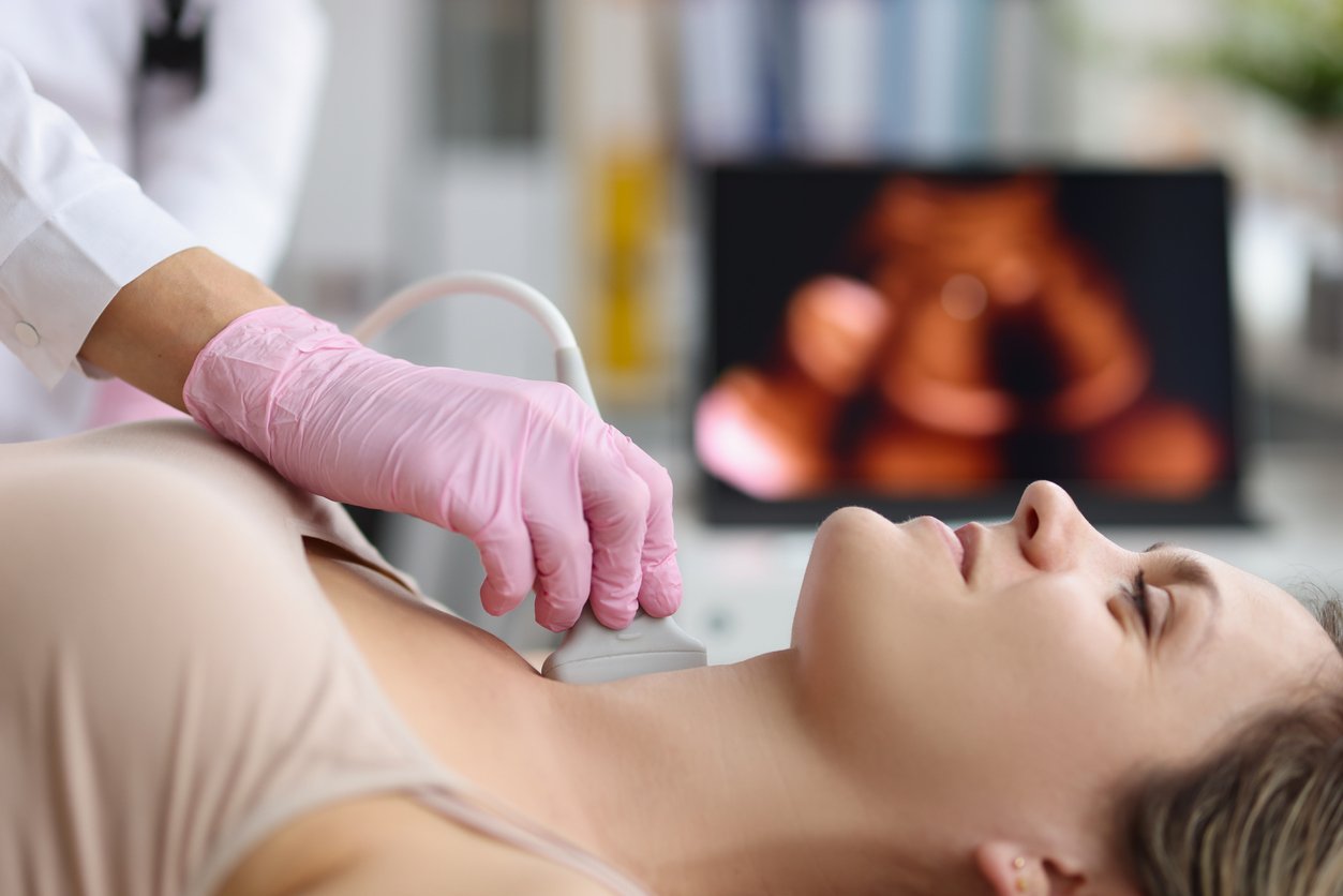 Doctor making ultrasound of thyroid gland to woman patient in clinic