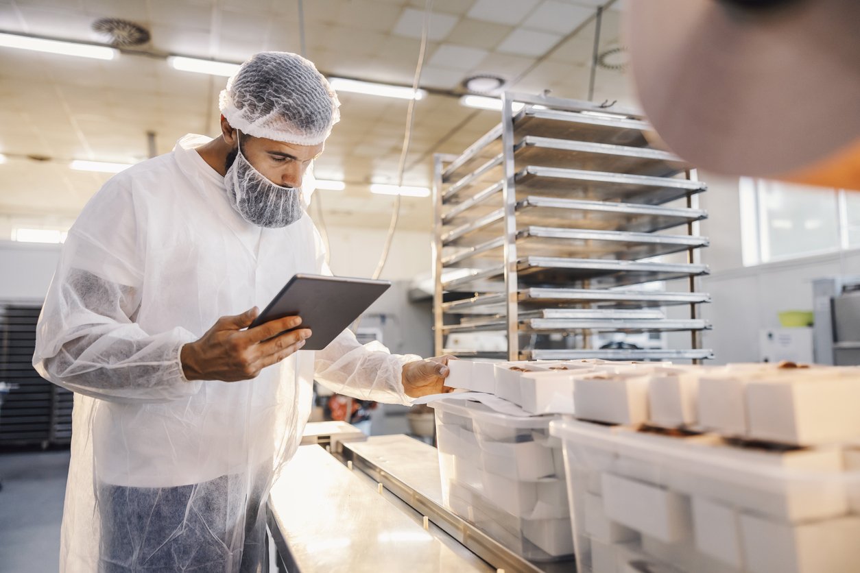 A food factory supervisor using tablet and assesses quality of food.