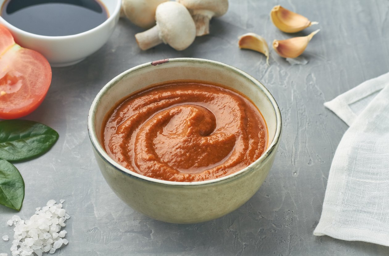 homemade umami paste with tomatoes parmesan cheese shitake mushrooms soy sauce garlic sea salt walnuts chicken broth miso paste in a bowl on grey background