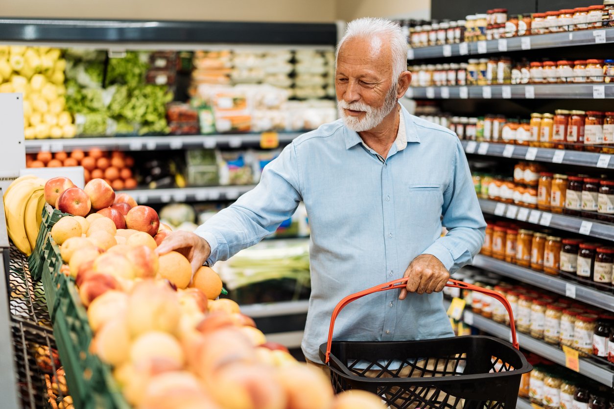 Пенсионер покупает продукты - фрукты и овощи