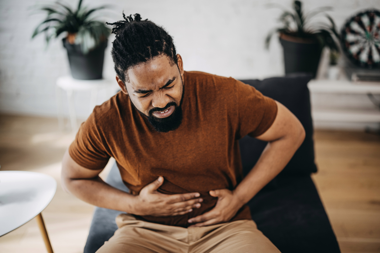 Black Man Having Stomachache Suffering From Painful Abdominal Spasm Standing Touching Aching Abdomen At Home. Abdomen Pain, Stomach Inflammation And Appendicitis Concept