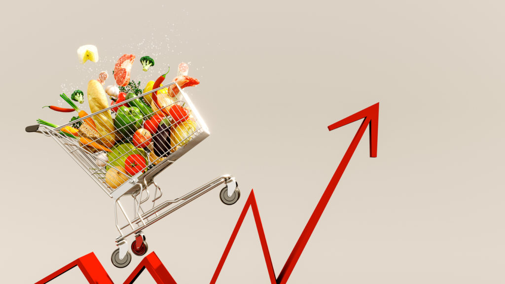 Rising cost of food concept image with a shopping cart full of groceries and a red arrow.