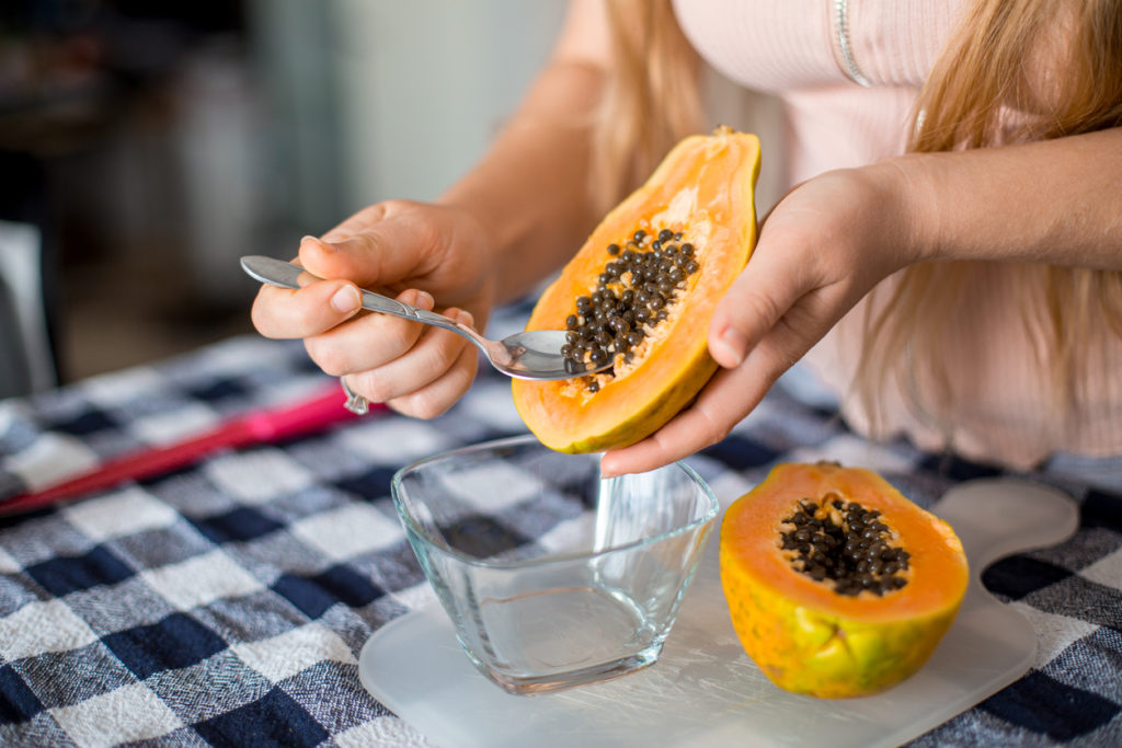 Removing papaya seeds into a glass container
