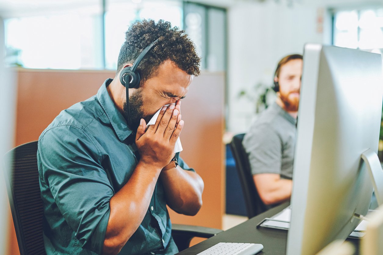 Sick call center agent blowing his nose