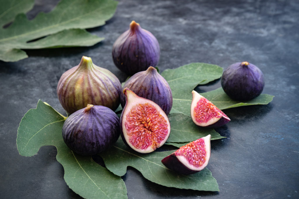 Whole and sliced figs on big fig leaves.
