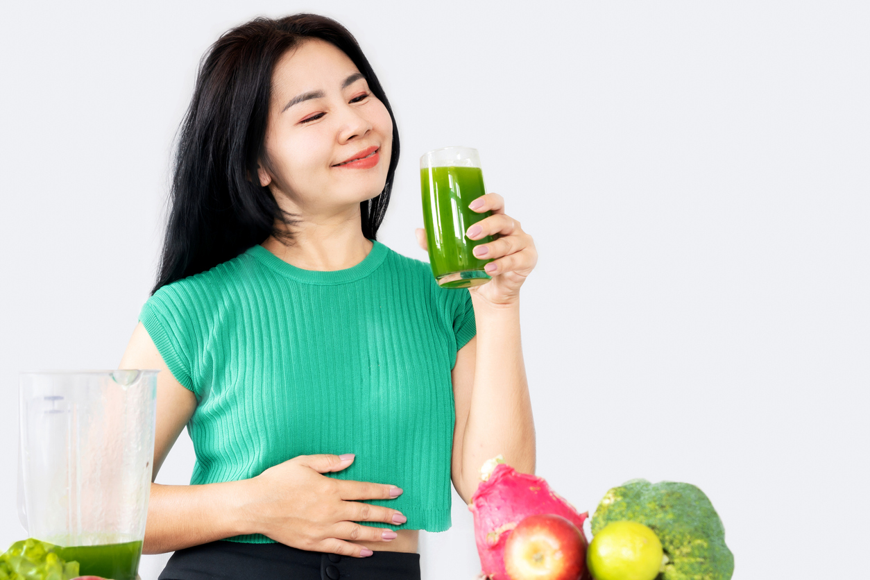 healthy Asian woman drinking mix of green vegetables and fruit juice for detox and diet