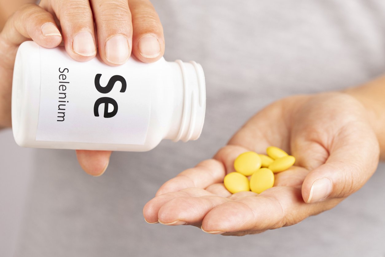 Woman hand takes Selenium Mineral Supplement from medicine container