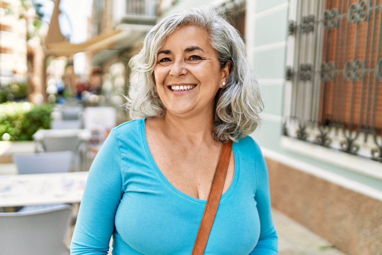 Middle age grey-haired woman smiling in a city