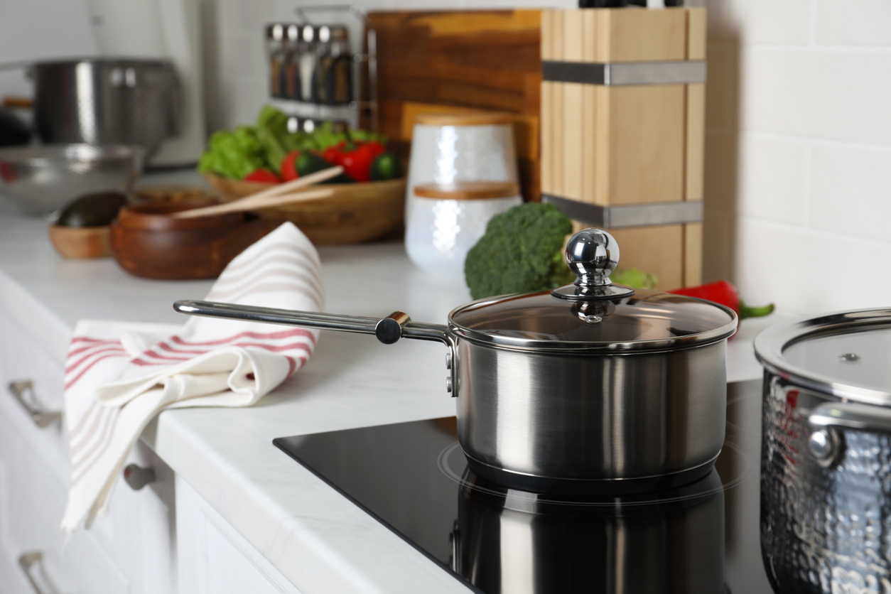 Metal saucepan on cooktop in kitchen. Cooking utensils