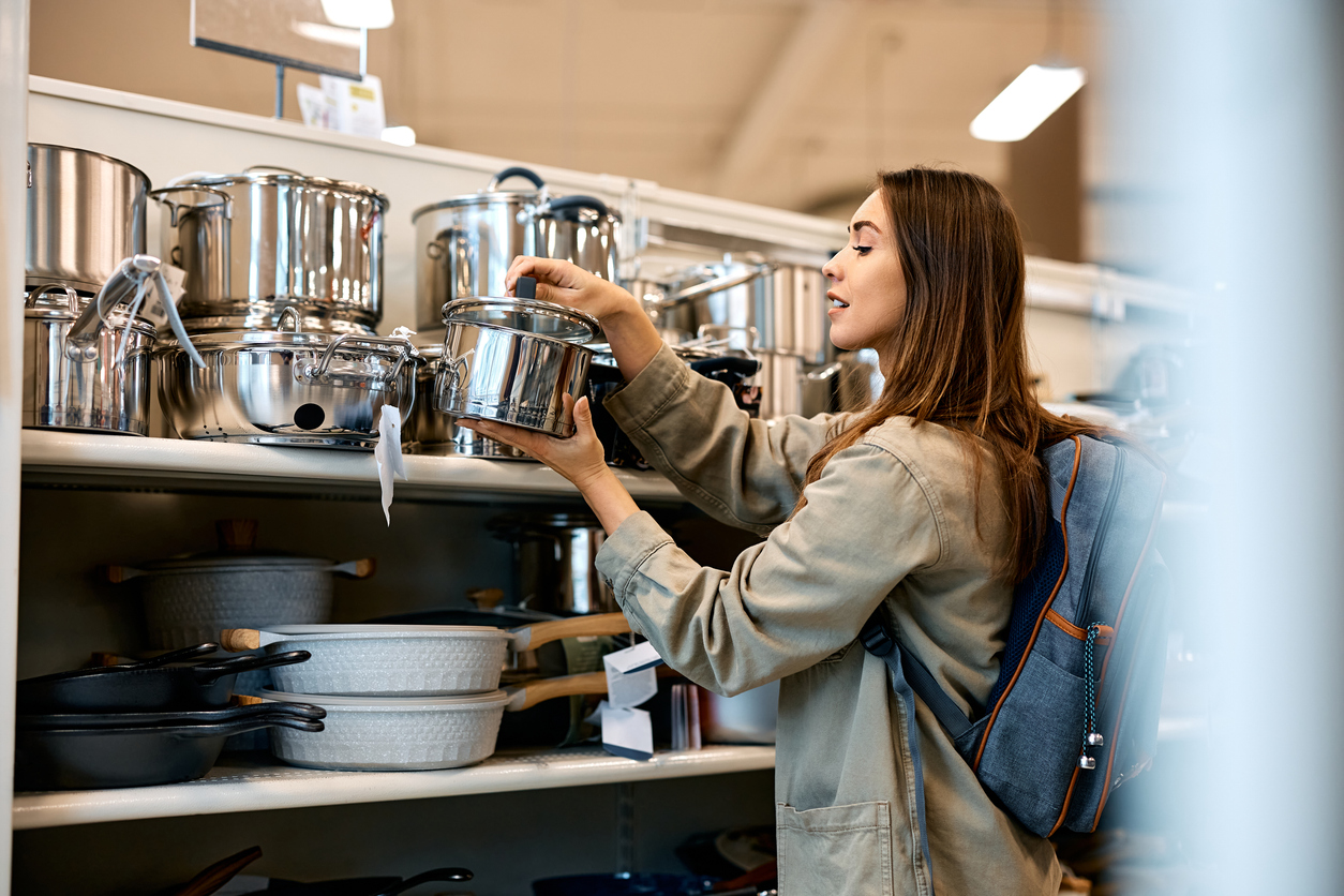 Young woman examining healthy cookware on a store shelf