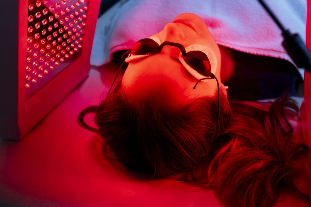 Woman using eye protection under red light therapy spa treatment