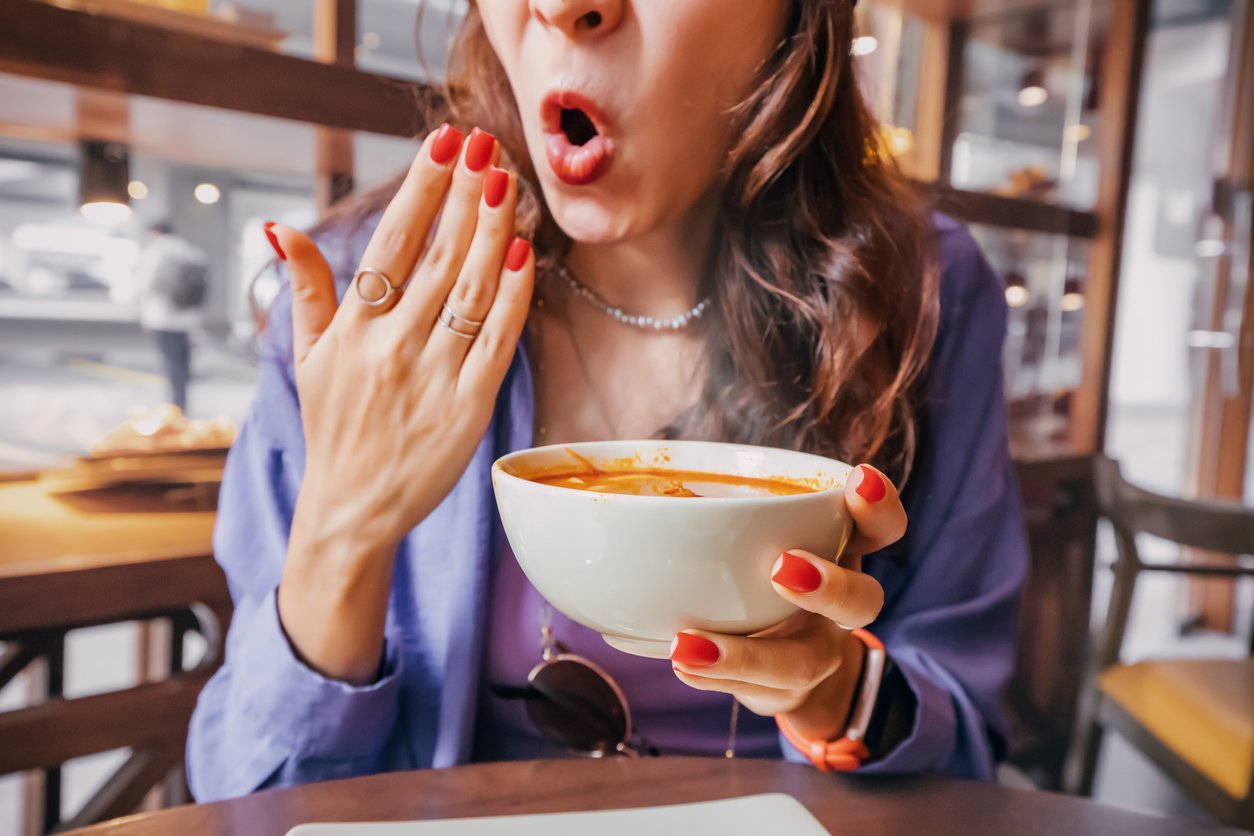 Woman eating a spicy soup in a restaurant