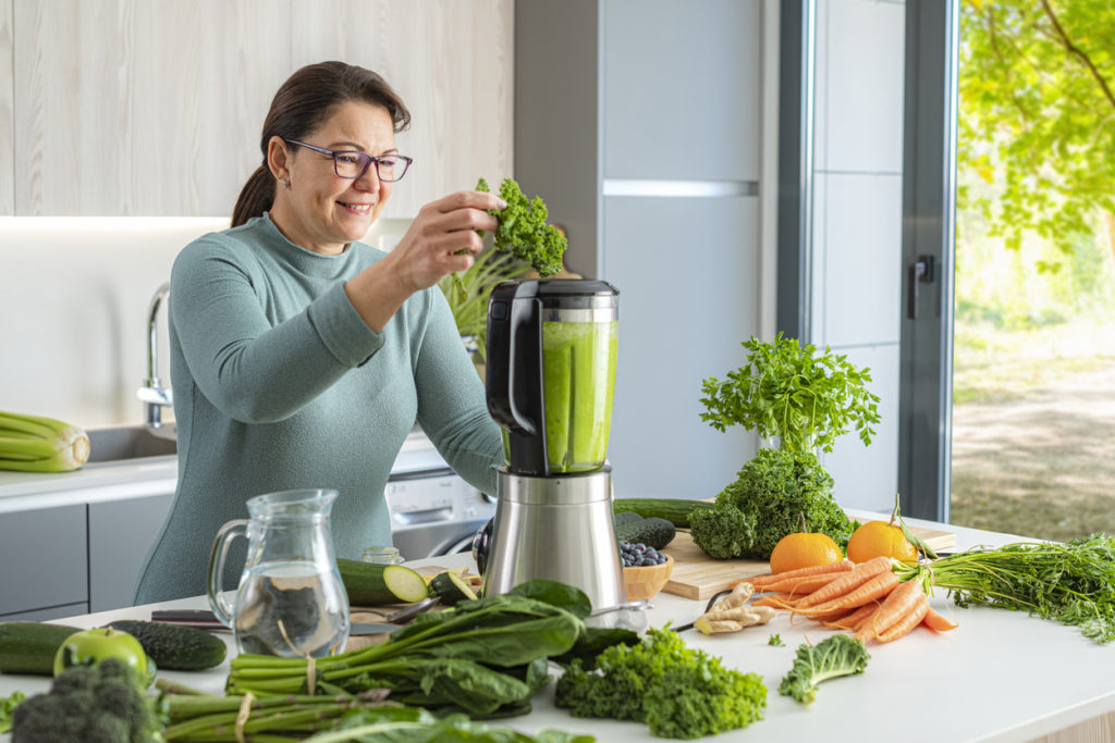 Portrait of a woman in domestic kitchen using blender for preparing green detox drink. High resolution 42Mp studio digital capture taken with SONY A7rII and Zeiss Batis 40mm F2.0 CF lens