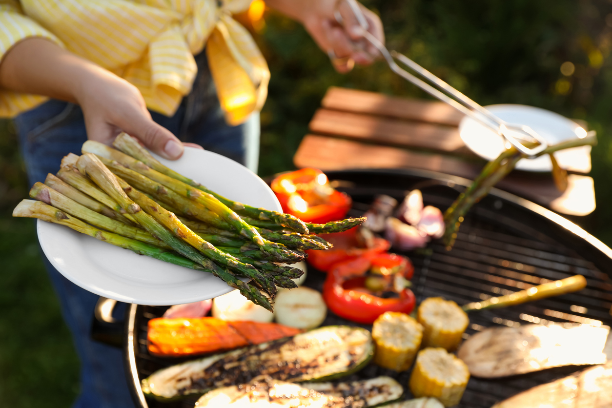 Woman cooking vegetables on barbecue grill outdoors, closeup