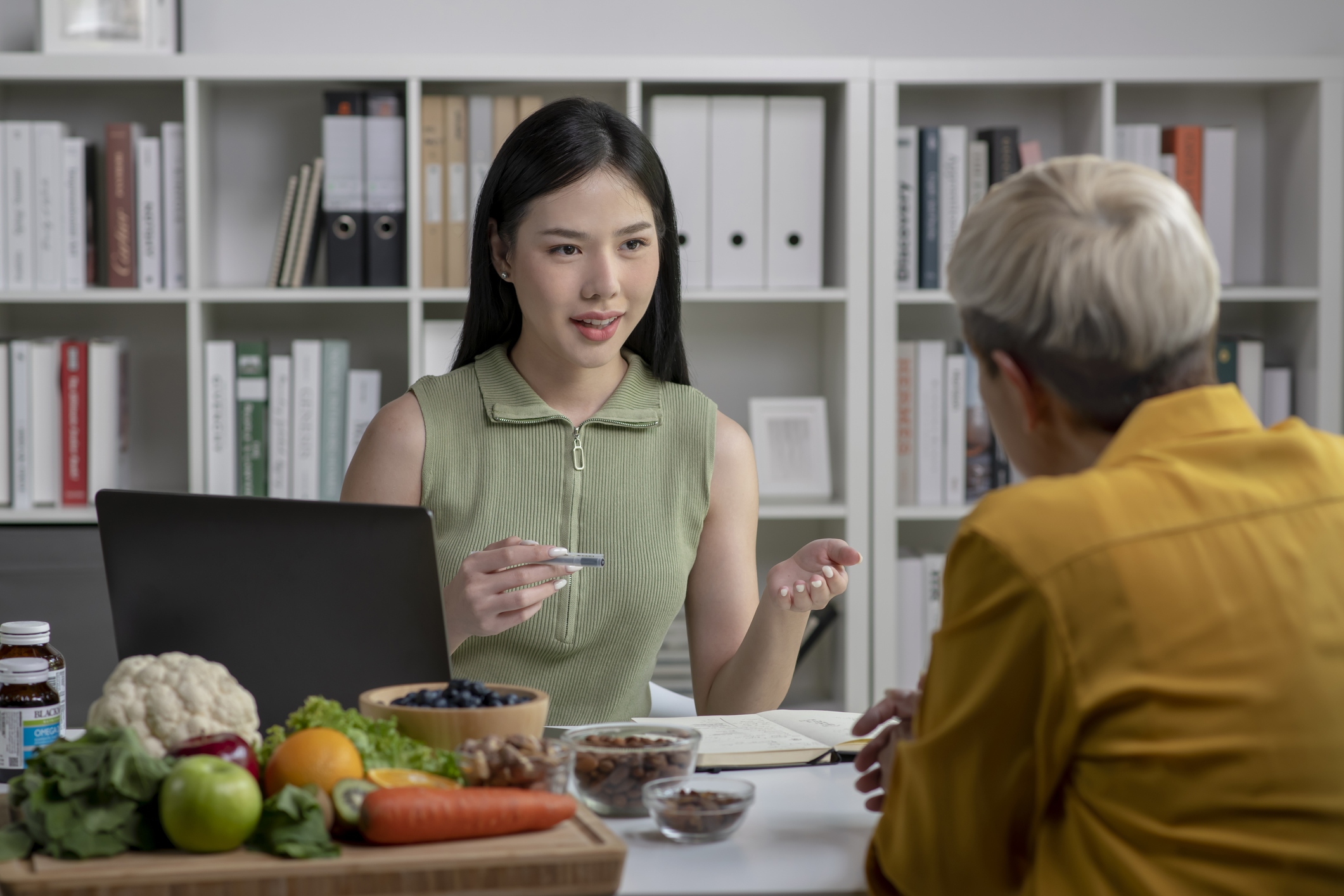 Nutritionist with woman client talking about meal plan and healthy products during a medical consultation in the office