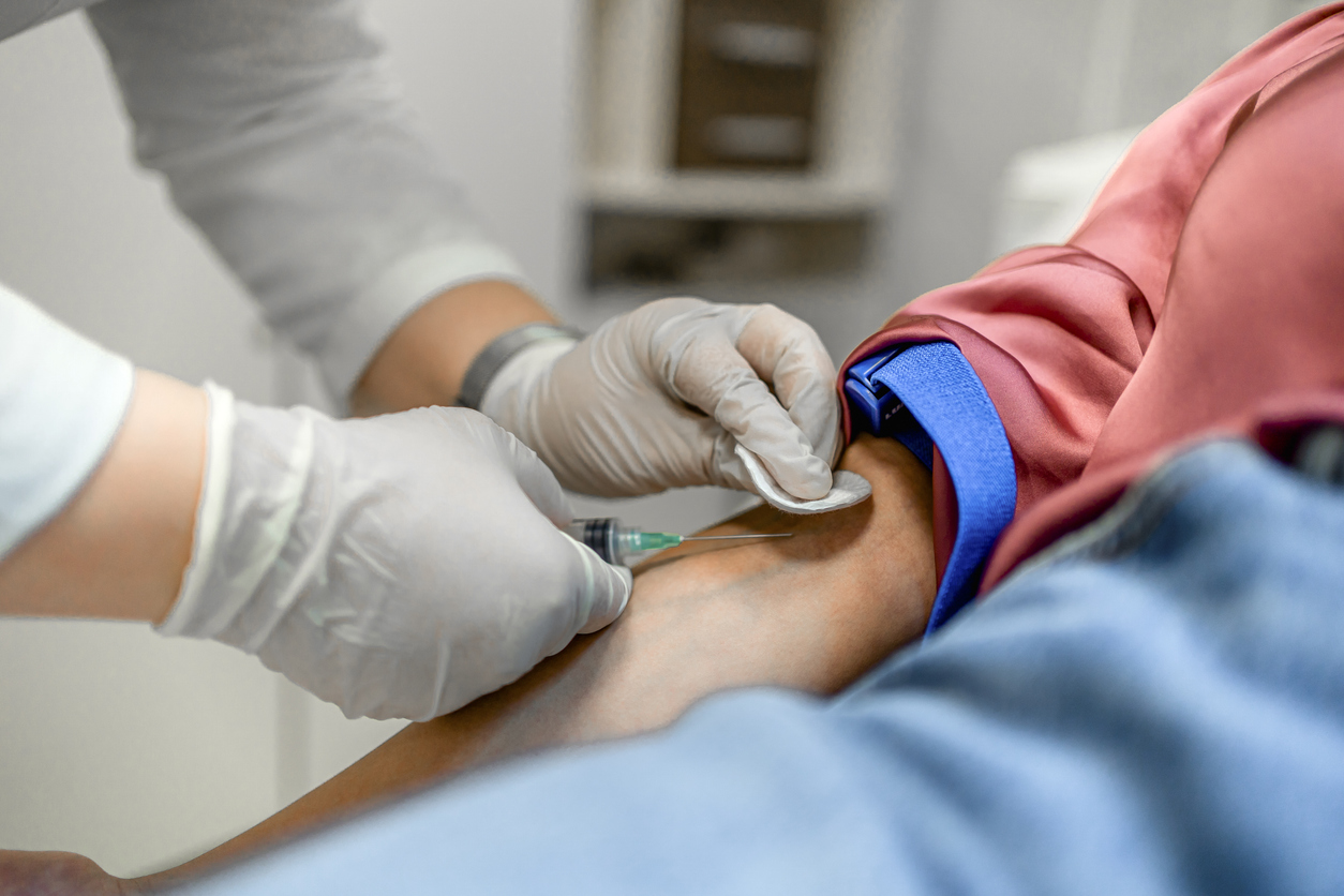 Nurse drawing blood from a female patient's arm vein in the medical clinic