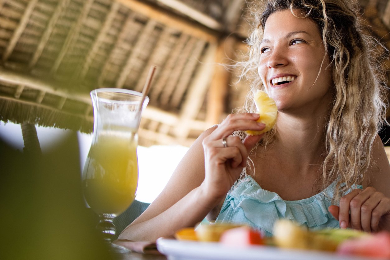 Happy woman enjoying while eating pineapple during snack time in a restaurant.