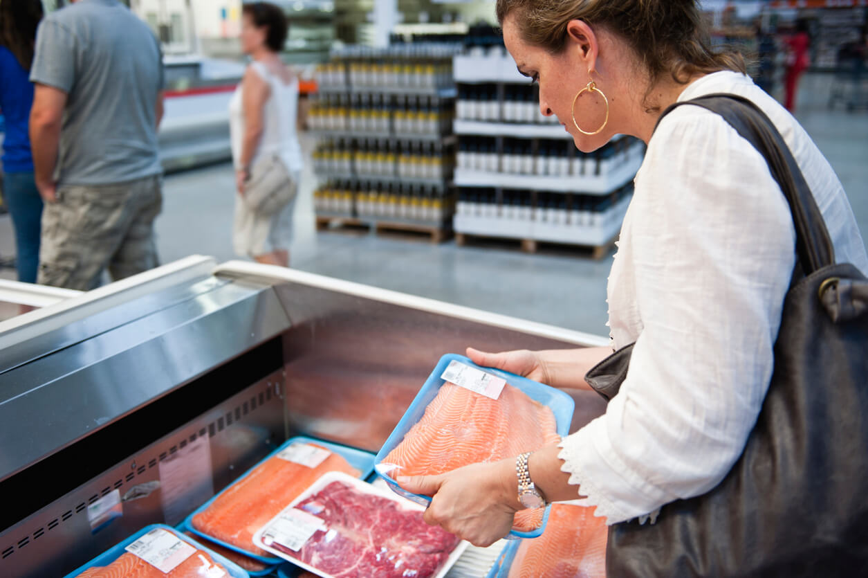 Woman purchasing fish from supermarket