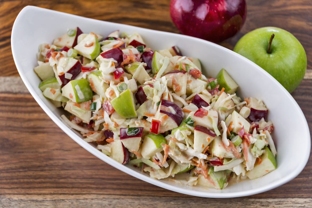 A bowl of fresh-made coleslaw with green and red apples.