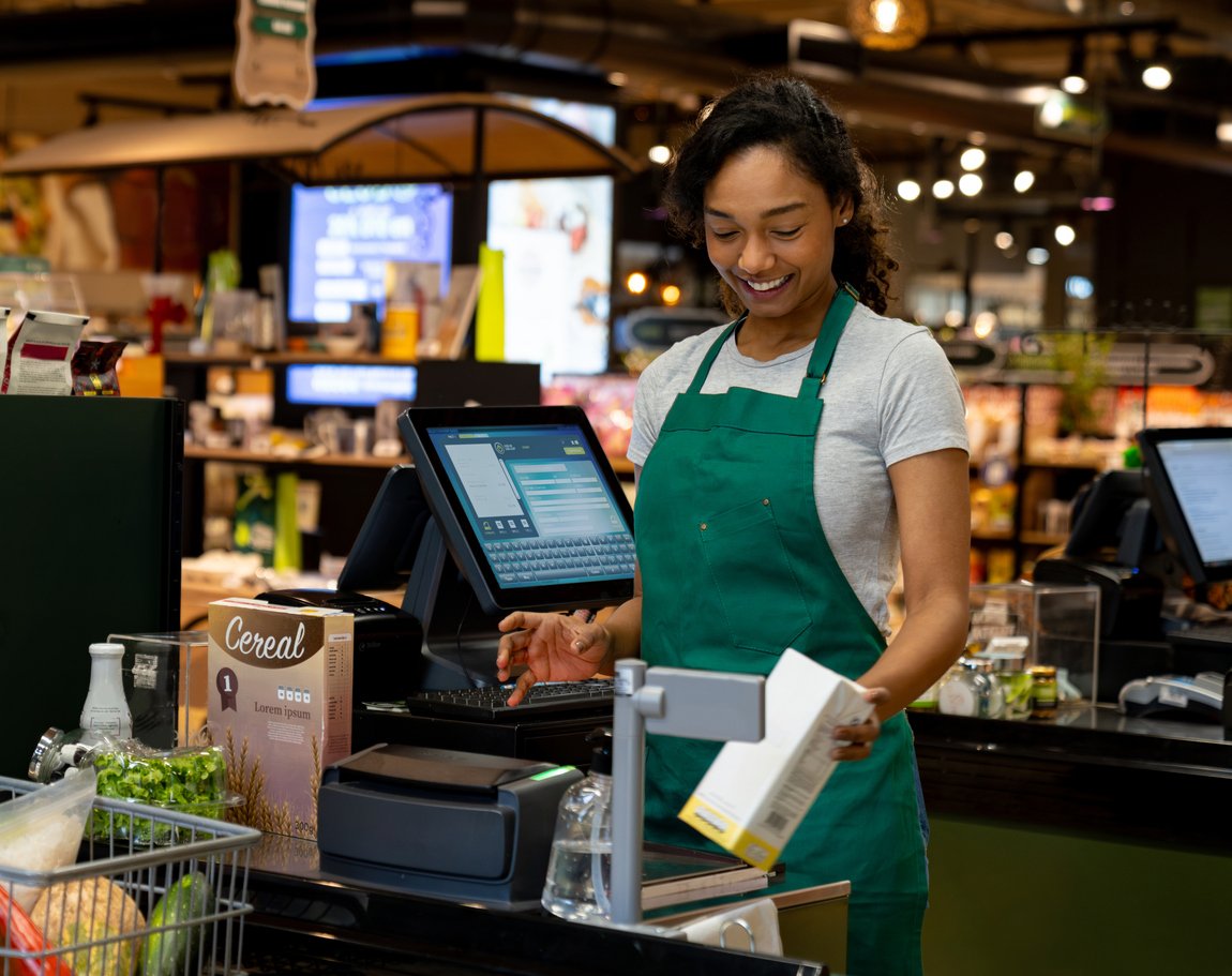 Happy cashier working at the supermarket ringing up groceries