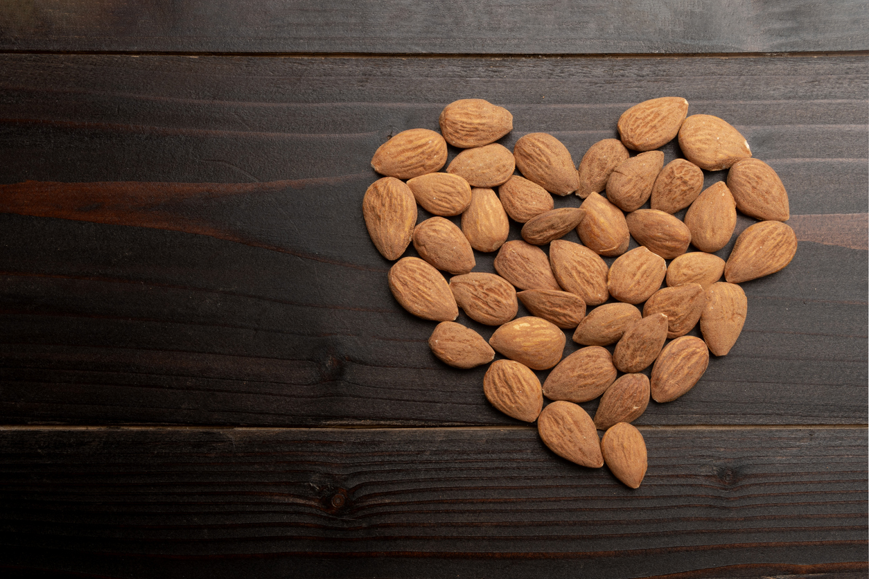 Heart made of raw almond on wooden background