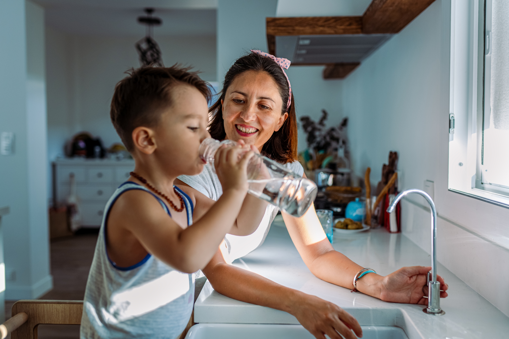 Mother and her toddler filling a glass with filtered water right from the tap