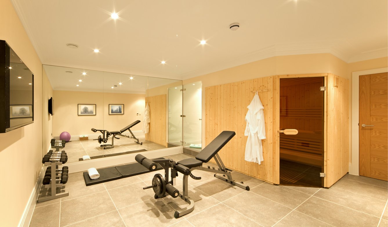 a gym in the basement of an exclusive new home, fitted with exercise equipment including weights, a bench, ball and floor mat. A pine-panelled sauna and shower room are also part of the complex. Trimmings include towels and a dressing gown.