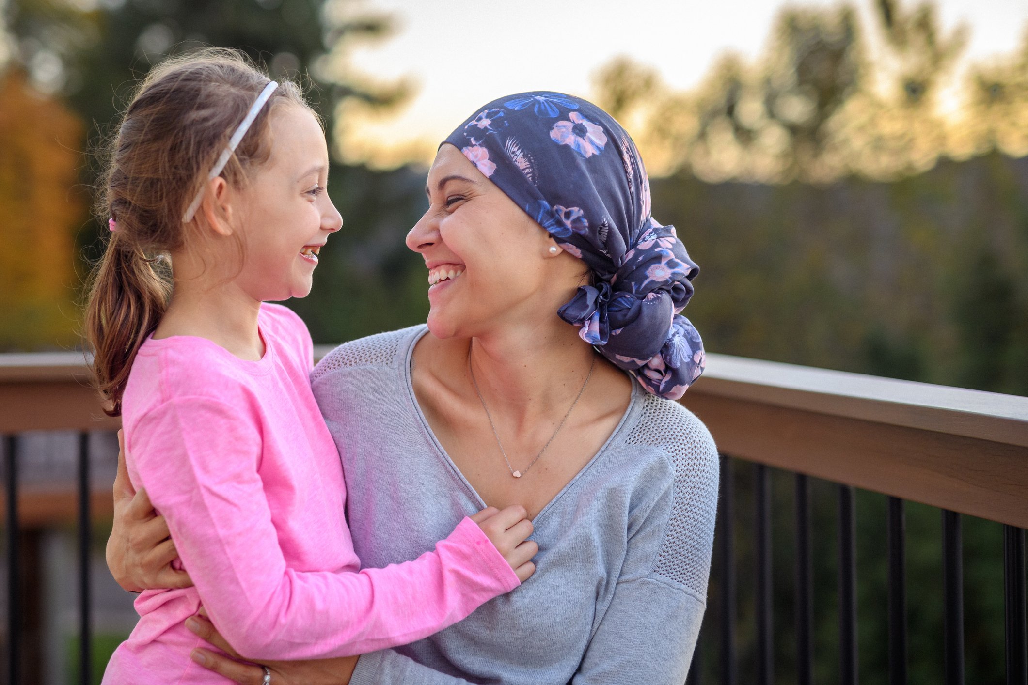 Young woman with cancer smiles at her young daughter