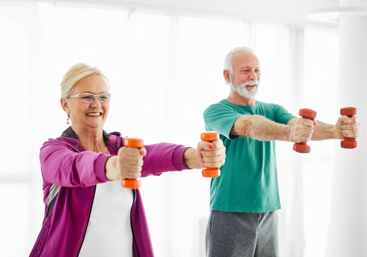 Senior couple exercise stretching and exercising with dumbbell lifting weight at home health care