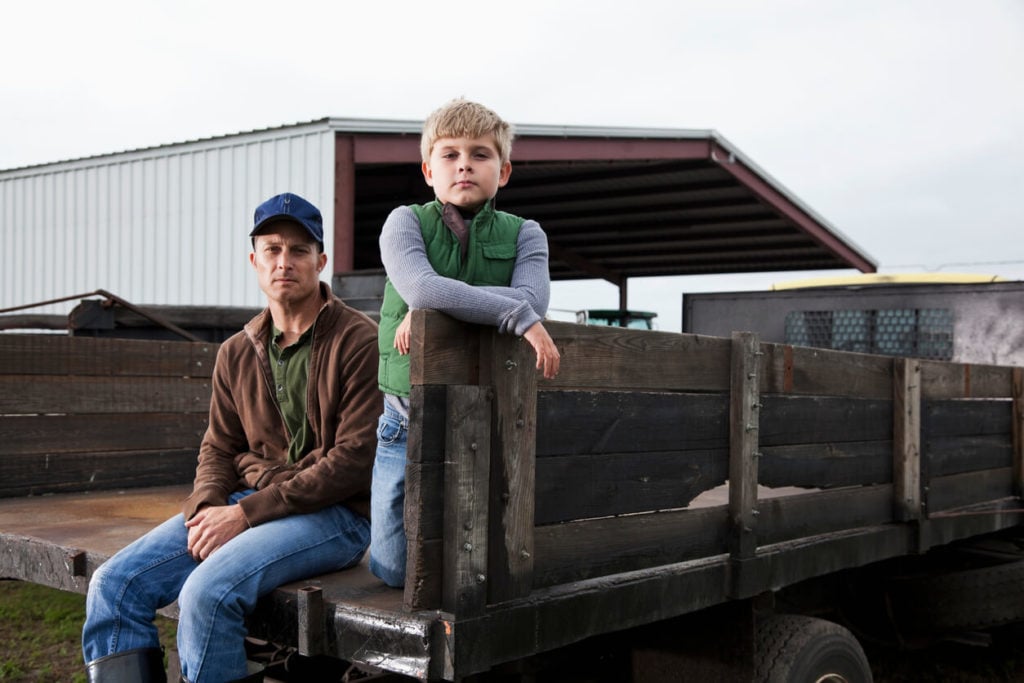 A young boy and his father on a family farm
