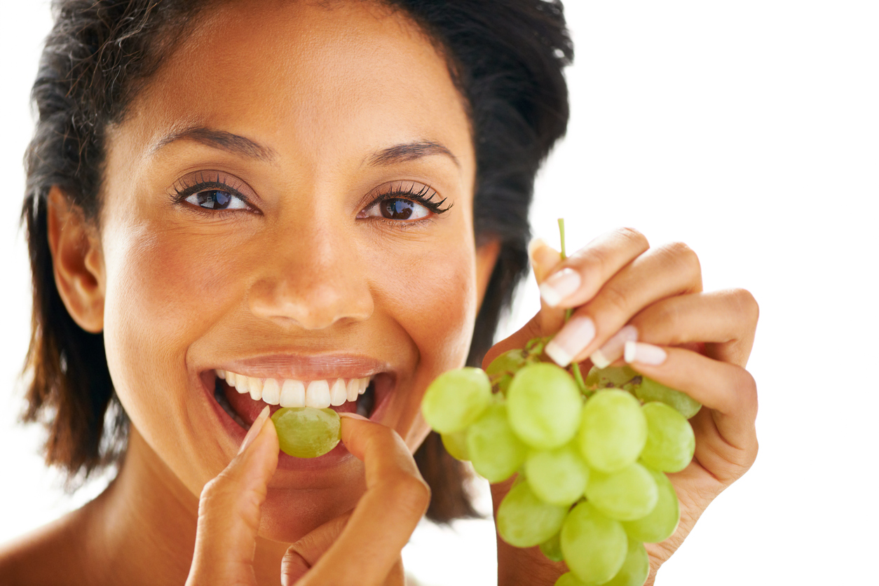 Closeup portrait of an attractive woman eating grapes