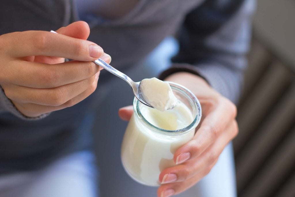 A spoonful of plant-based yogurt from a glass jar
