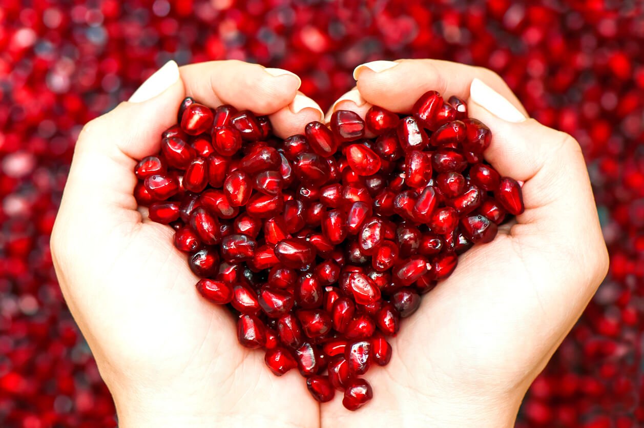 pomegranate seeds shaping heart in hands