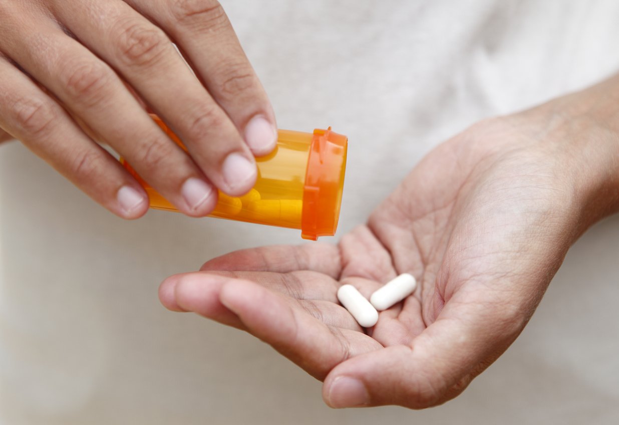 Women pouring medicine into hand.