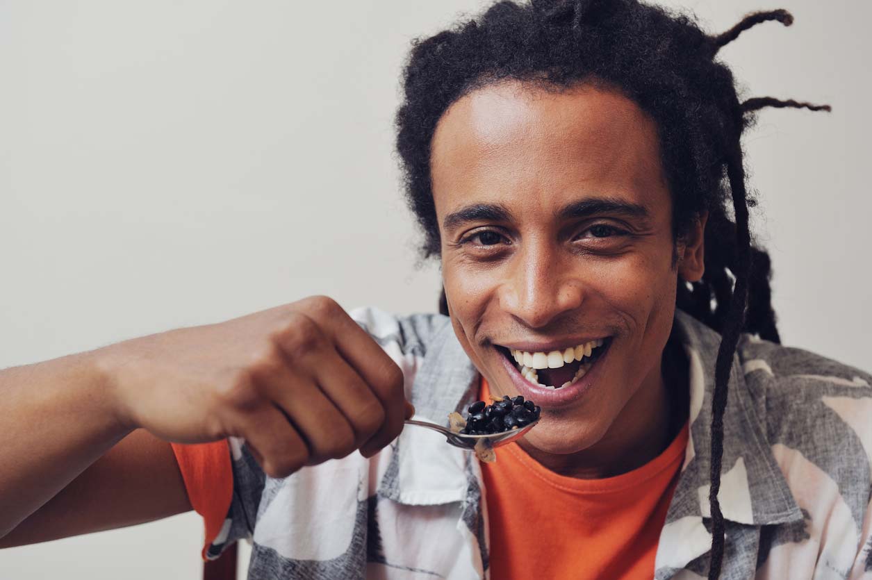 man happily eating spoonful of black beans