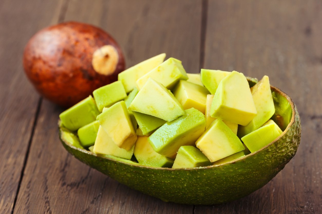 Chopped Avocado fruit with core on brown wooden old table.