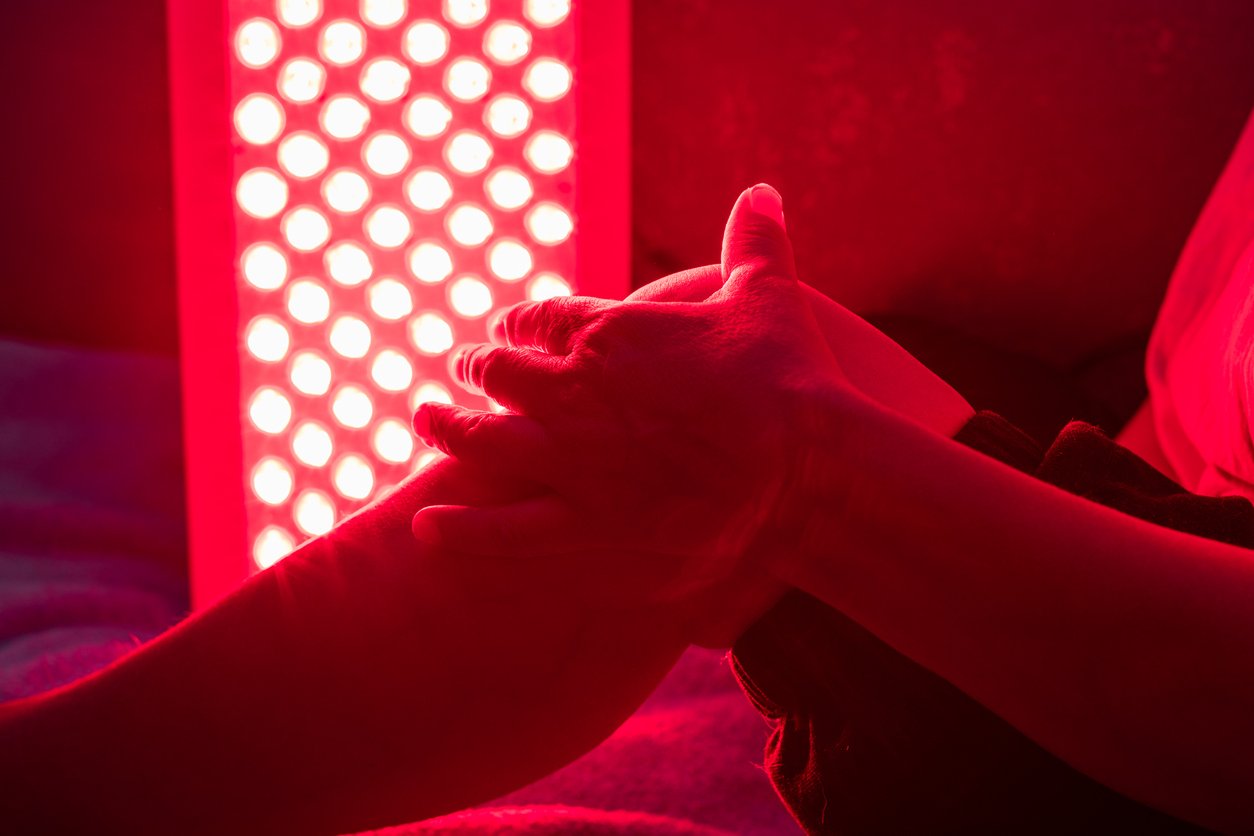 Person treating their knee with red light therapy panel